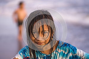 Beach lifestyle portrait of young beautiful and happy 7 or 8 years old Asian American mixed child girl with wet hair enjoying