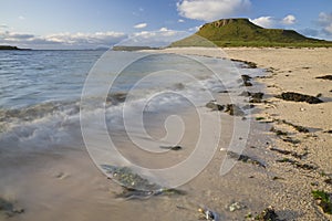 Beach line with blue sky, clouds and green grass