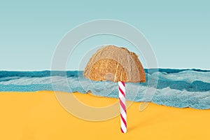 Beach with a lonely sun umbrella abstract concept. Candy cane and half of fresh raw organic coconut in front with blue ocean color