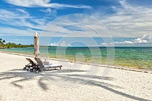 Beach Lounge Chairs under palm tree leaves at the shore of India