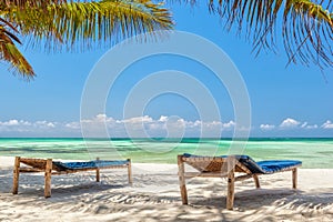 Beach Lounge Chairs under palm tree leaves at the shore of India