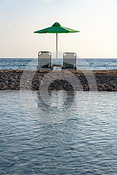 Beach lounge chairs under umbrellas on sandy peninsula between sea and river near Georgioupoli, Crete