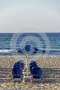 Beach lounge chairs under umbrellas on the seashore