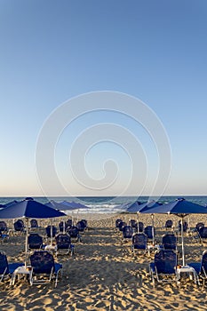 Beach lounge chairs under umbrellas on the seashore