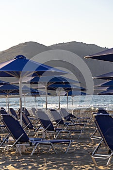 Beach lounge chairs under umbrellas on the seashore