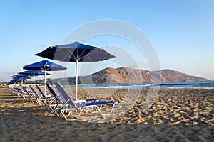 Beach lounge chairs under umbrellas on the seashore