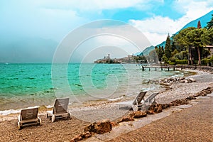 Beach lounger at lake shore gardasee with wavy water, malcesine