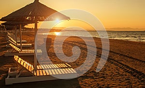 Beach loungers on empty sand coast by sea in bright sunset light, Montenegro, Ulcinj,.Long beach