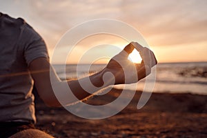 Beach meditation, sunset and hands of man meditate for peace, freedom and chakra energy healing of soul aura. Sun flare