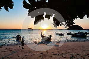 Beach in the morning with man jogging and boat with sunrise in L