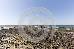 Beach With Mud Flats With Water Marker At Peak To Warn Boats