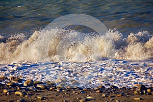 Sea rolling and receding water in rays of setting sun.