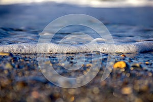 Sea rolling and receding water in rays of setting sun.