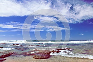 Beach near Mosselbay South Africa during morning sunshine under a cloudy sky.