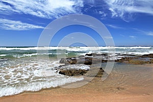 Beach near Mosselbay South Africa during morning sunshine under a cloudy sky.