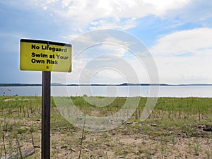 Beach, no lifeguard, swim at your own risk signage.