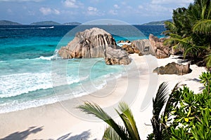 A beach with palms, big stones, turqouise water and waves photo