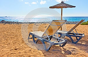 Beach with parasol and chaise longues by the sea photo