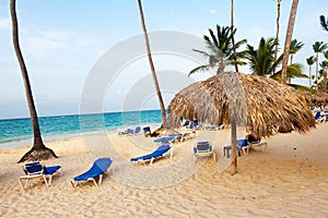 Beach parasol on the white sand beach with cloudy blue sky and sun