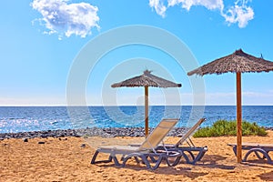 Beach with parasols and chaise longues by the sea
