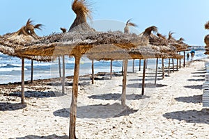 Beach with parasols from palm leaf on Mediterranean