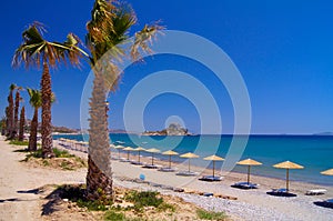 Beach with parasols and palms on the island of Kos in Greece