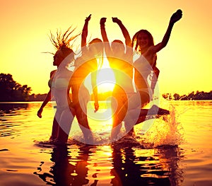 Beach party. Happy girls in water over sunset photo