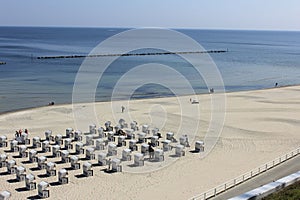 a beach with people on the sand and chairs sitting around