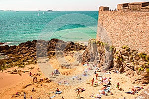 The beach and people sunbathing under city walls St Malo, France