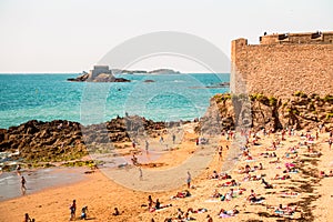 The beach and people sunbathing under city walls St Malo, France