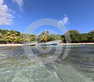 beach of petit havre with two ships seen from the clear sea water, caribbean island in guadeloupe