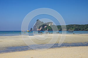 Beach of Phi Phi island in low tide with bay and longboat on background, Krabi province, Thailand