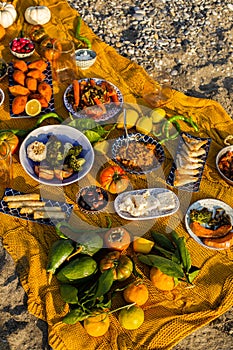 Beach picnic with various Mediterranean dishes and autumn fruits and vegetables