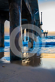 Beach pier pillars and crashing ocean waves
