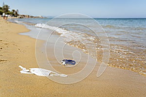 Beach polluted with face masks of covid. Environmental contamination problem