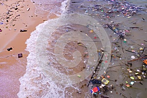 Beach pollution â€” trash of plastics, bottles, other wastes, washed ashore from tropical sea