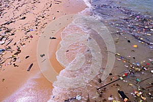 Beach pollution â€” trash of plastics, bottles, other wastes, washed ashore from tropical sea