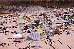 Beach pollution â€” trash of plastics, bottles, other wastes, washed ashore from tropical sea