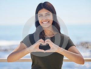 Beach portrait and heart hand woman for summer holiday freedom, happiness and wellness. Happy Indian girl enjoying sun