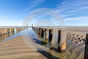 Beach with pure sand, footprints and breakwater with a blue sky in the morning