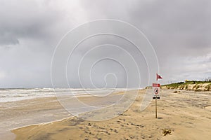 Beach red flag danger swimming sign in a cloudy day