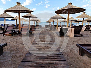 Beach with reed umbrellas and the sun beds. In the background the sea, blue sky and horizon