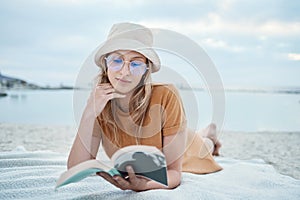 Beach, relax and woman reading a book in peaceful summer holidays or vacation outdoors in nature with freedom. Travel