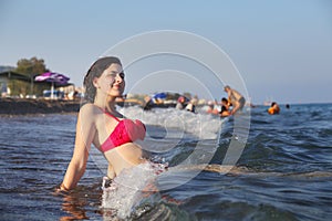 Beach resort, caucasian girl resting, sitting on surf line.