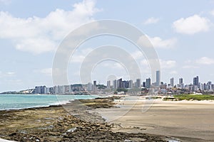 Beach, rocks, skyscrapers and clouds photo