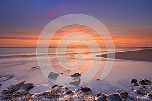 Beach with rocks at sunset in Zeeland, The Netherlands