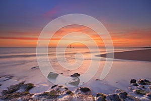 Beach with rocks at sunset in Zeeland, The Netherlands photo
