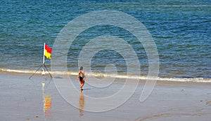 Beach with safe bathing flag and lone figure