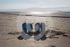 on the beach in the sand buried two pairs of beach slippers at sunset photo taken, beautiful and creative beach