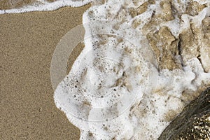 Beach sand sea water summer background. Sand beach desert texture. White foam wave sandy seashore top view.